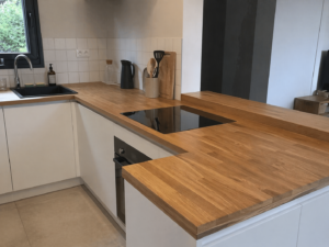 Cuisine moderne avec plan de travail bois clair et plaque de cuisson noire